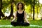 Attractive and tranquil woman sits in lotus position under tree. Yoga and meditation, concentration and relaxation, unity with