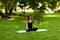 Attractive and tranquil woman sits in lotus position under tree. Yoga and meditation, concentration and relaxation, unity with