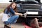 Attractive trendy young woman fixing her car