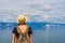 Attractive tween tourist girl in hat and backpack standing on cliff top and admiring beautiful landscape of blue sky and Baikal