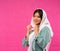 attractive veiled Asian girl with hands fixing veil on pink