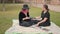 attractive white girls sitting on sheet on the grass in the park. Human interaction, friendship. Pullback shot