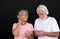 Attractive white-haired senior couple using smartphone with earphones. Two happy retirees enjoying free time and technology, new