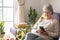 Attractive white-haired senior woman at home sitting on the sofa using her smartphone. Modern retired people enjoying wireless