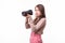 Attractive woman aims her camera composing a photograph in studio, isolated on white background