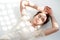 Attractive woman in beatiful white dress lying on the light floor with closed eyes and circle sunlights fall on her