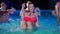 Attractive woman in bikini flirting and hanging out with friends at night pool party. Attractive female partying in a