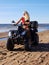 Attractive woman in bikini with long blonde hair is sitting on the quad bike, sunny day