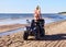 Attractive woman in bikini with long blonde hair is sitting on the quad bike, sunny day