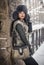 Attractive woman with black fur cap and gray waistcoat enjoying the winter. Side view of fashionable brunette girl posing