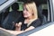 Attractive woman with blond hair sits behind the wheel of a car and speaks indignantly on the phone