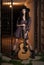 Attractive woman with country look, indoors shot, american country style. Girl with black cowboy hat and guitar