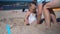 Attractive woman digging little girl deep in sand. Mother and daughter have fun