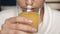 Attractive woman is drinking orange juice. Female hands bring glass of orange juice to face and drink it. Close-up