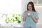 Attractive woman eating tasty yogurt in kitchen. Space for text