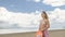 Attractive woman in a hat stands on the beach against the blue sea.