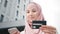 Attractive woman in hijab and formal clothes holding modern smartphone and credit card in hands. Muslim woman doing
