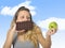 Attractive woman holding apple and chocolate bar in healthy fruit versus sweet junk food temptation