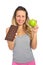 Attractive woman holding apple and chocolate bar in healthy fruit versus sweet junk food temptation