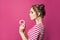 Attractive woman holding donut on vivid pink background, diet concept