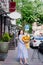 attractive woman with huge bouquet of decorative sunflowers walks along city