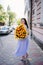 attractive woman with huge bouquet of decorative sunflowers walks along city