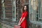 Attractive woman leaning on wooden wall of old log cabin with retro suitcase