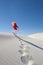 Attractive woman leaving footsteps up a sanddune