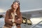 Attractive woman pilot wearing sunglasses standing in the sunshine on an airfield resting against her small private airplane