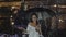 Attractive woman poses with umbrella under flowing fountain in deep evening