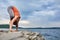 Attractive woman is practicing yoga on the stone near beautiful river.