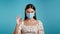 Attractive woman in protective respirator showing Okay sign over blue background. Positive young girl in mask smiles to