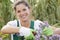 Attractive woman pruning flowers in garden with shears