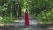 Attractive woman in red dress walks forest, female in evening outfit, high heels