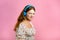 Attractive woman with red hair with headphones on pink studio background. Cute girl portrait. Music, radio, happiness