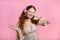 Attractive woman with red hair with headphones on pink studio background. Cute girl portrait. Music, radio, happiness