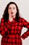An attractive woman in a red plaid dress opened her mouth in surprise