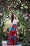 Attractive woman in red skirt in floral garden. Fairy tale