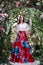 Attractive woman in red skirt in floral garden. Fairy tale