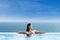 Attractive woman relaxing at infinity swimming pool