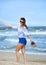 Attractive woman in shorts walking happy on beach sand wearing s