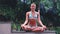 attractive woman sitting lotus yoga pose in spiritual relaxation serenity and meditation at stunning beautiful waterfall