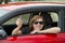 Attractive woman smiling proud sitting at driver seat holding and showing car key in new automobile buying and renting