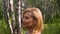 Attractive woman smiling and walking in birch grove in summer park. Profile view