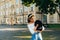 Attractive woman standing on the street with a small dog in her arms. Lady with a dog breed toy poodle in her arms walking