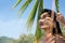 Attractive woman standing under a palm leaf