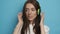 Attractive woman on a strong background in stylish green headphones listens to music. Active lifestyle