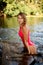 attractive woman in swimsuit posing stretching out of water and leaning her hands on edge of boat