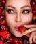 Attractive woman tasting cherry and strawberry. Beautiful woman with fashion makeup and a vivid background