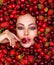 Attractive woman tasting cherry and strawberry. Beautiful woman with fashion makeup and a vivid background